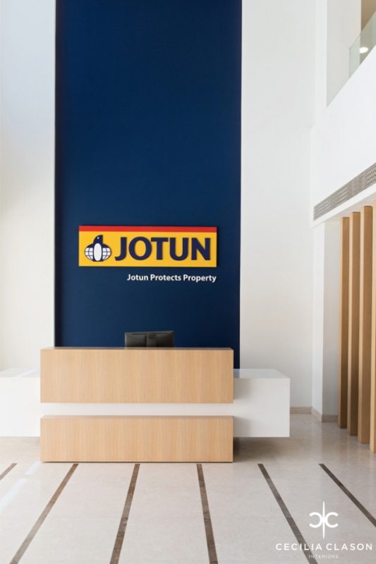 Office Reception Design - White desk with wooden partition & deep blue wall, with Jogun logo behind it & folding doors
