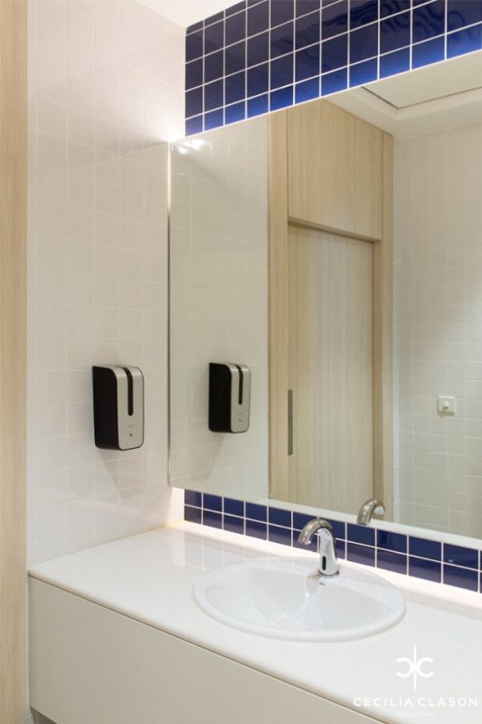 Office Bathroom Design | White tiled walls & deep blue tiles around mirror with white granite top bathroom counter