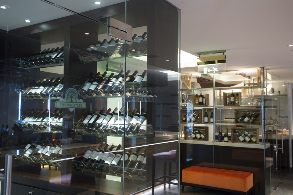 Bar Interior Design - Glass wine cellar with orange velvet chair and modern ceiling lighting
