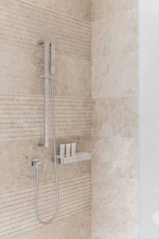 Hotel Bathroom Interior Design - Shower interior design with modern silver shower column, and patterned & tiled marble walls