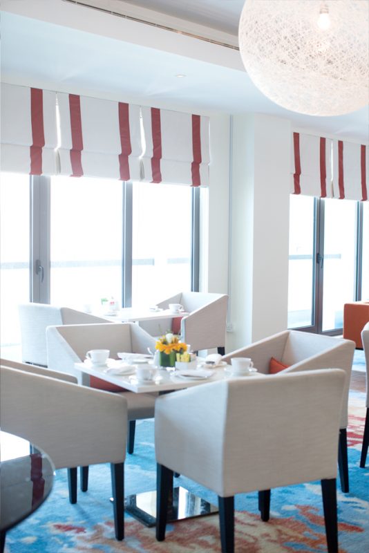 Business Lounge Design - Luxury chairs & tables on large abstract rug below white netted ball lighting