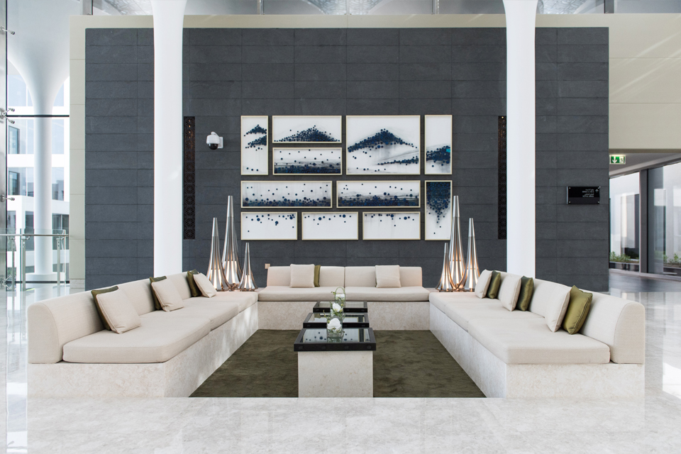 Living Room Design - White leather couches with marble floors, grey feature wall with hanging wall art & white pillars