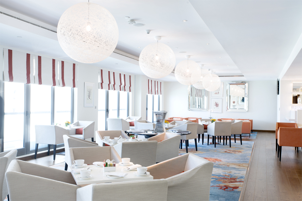 Business Lounge Design - Luxury chairs & tables on large abstract rug below white netted ball lighting