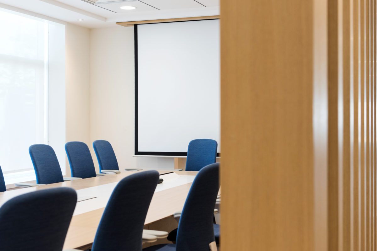 Boardroom Design - Boardroom seen past wooden folding door, boardroom table with blue chairs and projector screen