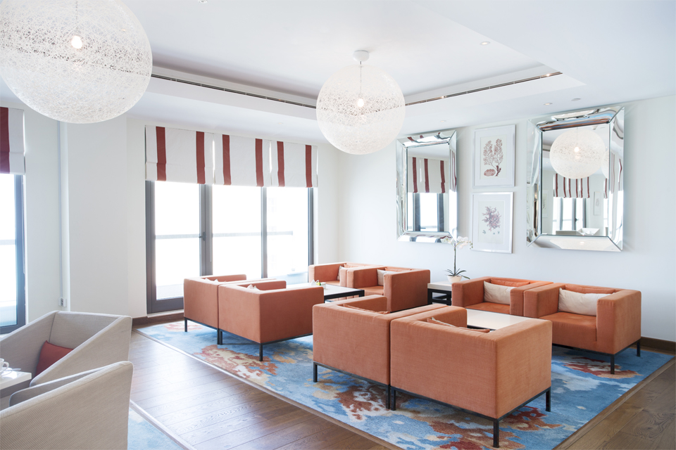 Executive Living Room Design - Luxury orange chairs on abstract rug below white netted hanging lighting